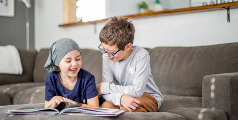 a child with cancer reads alongside her brother