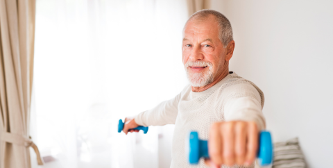 a mid-60s man using hand weights at home for fitness